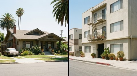A traditional single-family home beside a modest nearby apartment building on a quiet street.