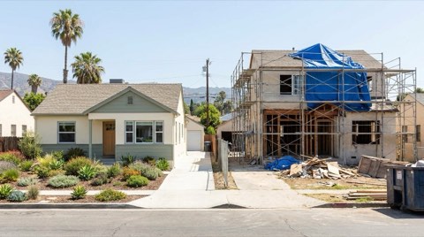 Two homes on the same block, one move-in-ready and the other mid-renovation with visible scaffolding.