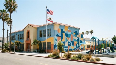 A cheerful elementary school exterior in Venice with a playground and palm trees