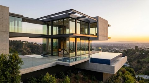 A striking modern view-home cantilevered over a hillside with glass walls and an expansive canyon view