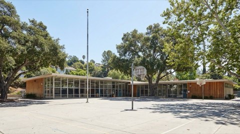 A well-maintained mid-century school building near Los Feliz with a shaded courtyard and basketball hoops