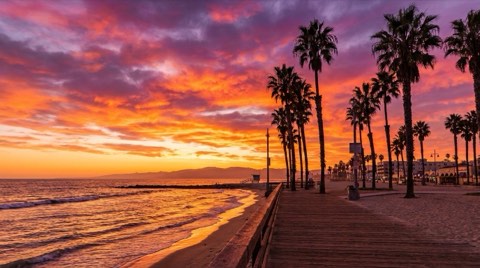 A vivid sunset over the Venice Beach boardwalk and shoreline