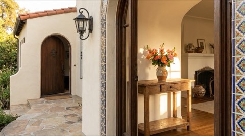 An open front entryway of a Spanish revival home in Los Feliz with fresh flowers on a table in warm afternoon light